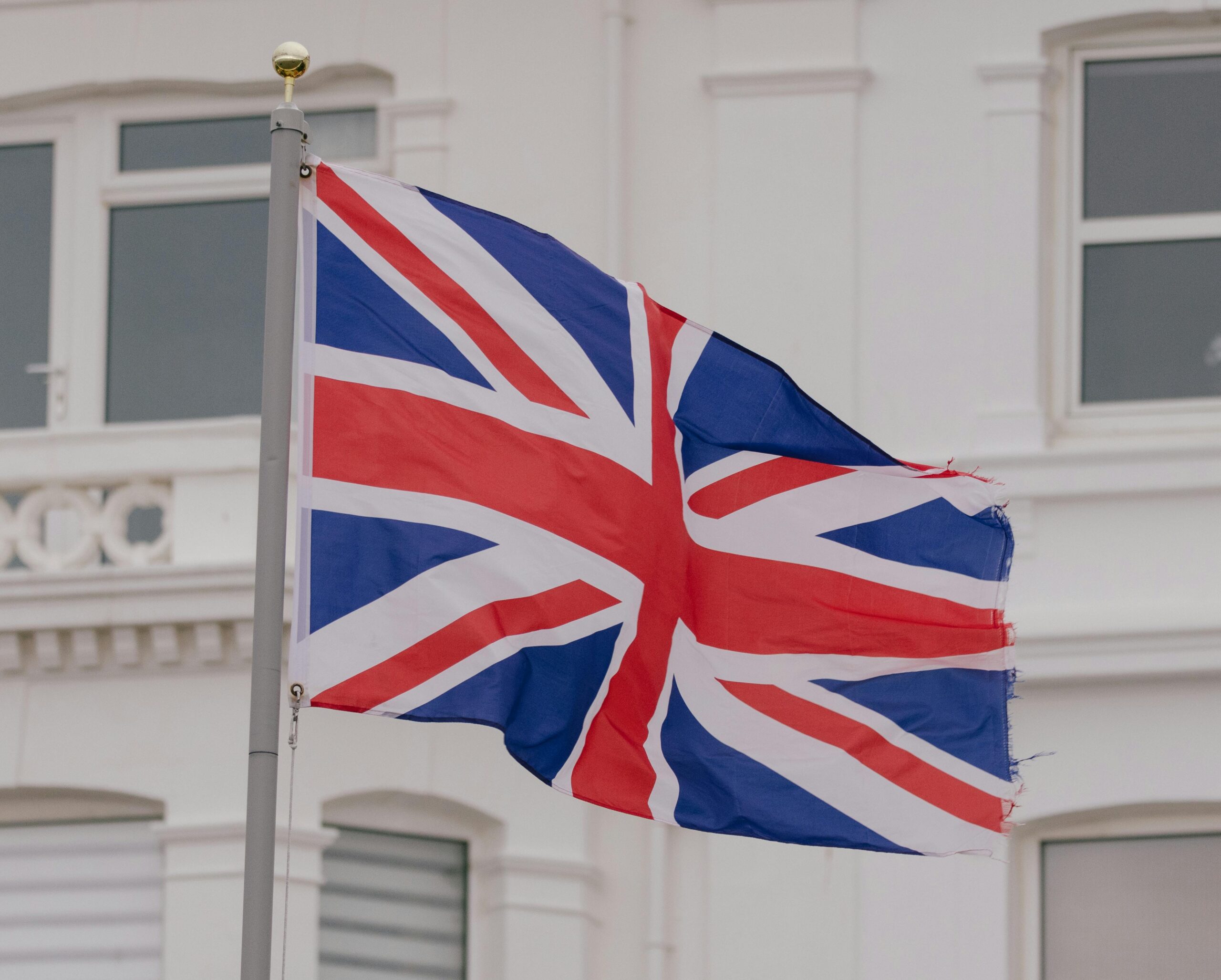 Close-up of the Union flag waving in front of a building in an urban area.
