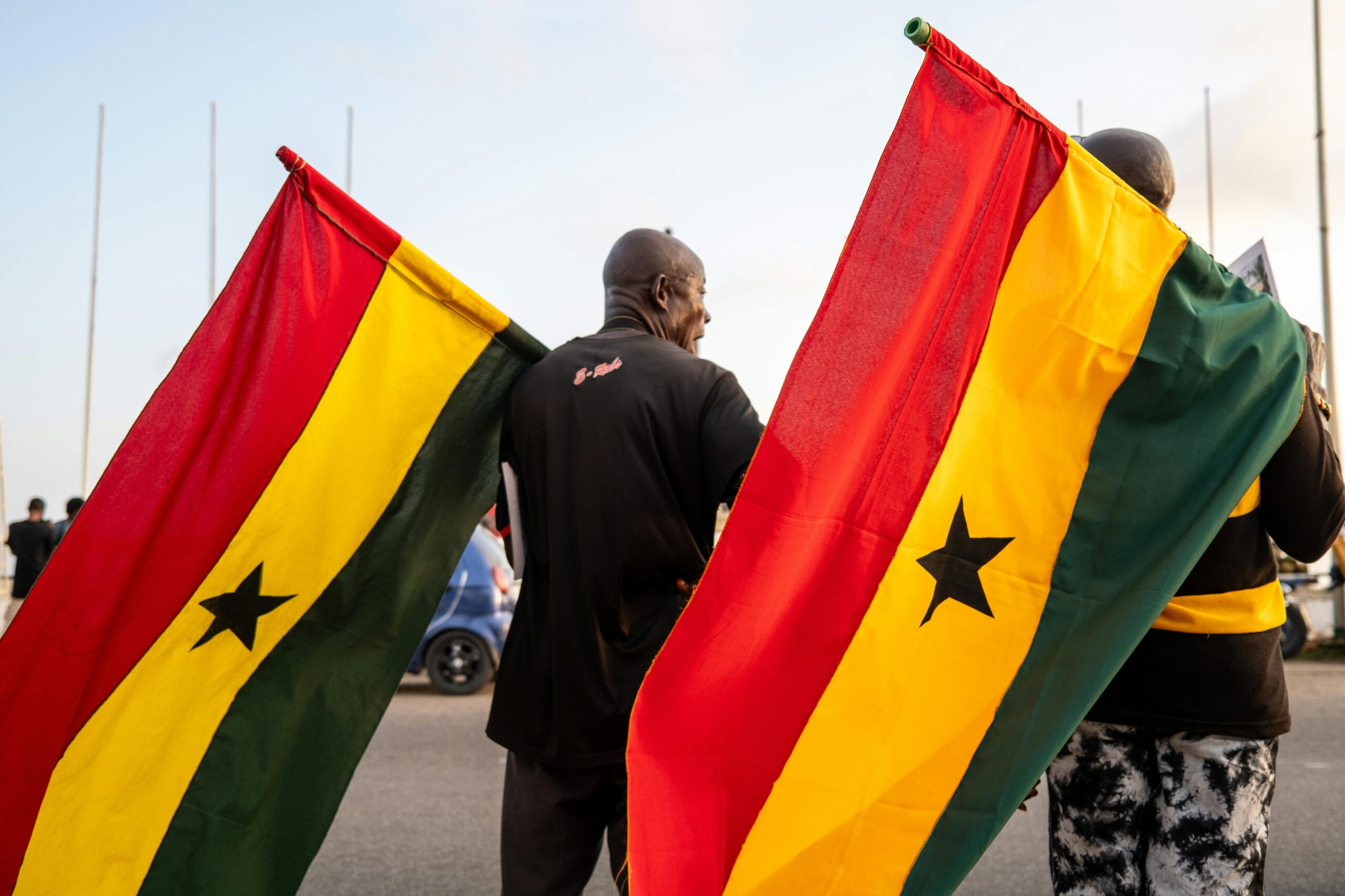 Two men holding Ghanaian flags during a public event in Ghana, capturing national pride.